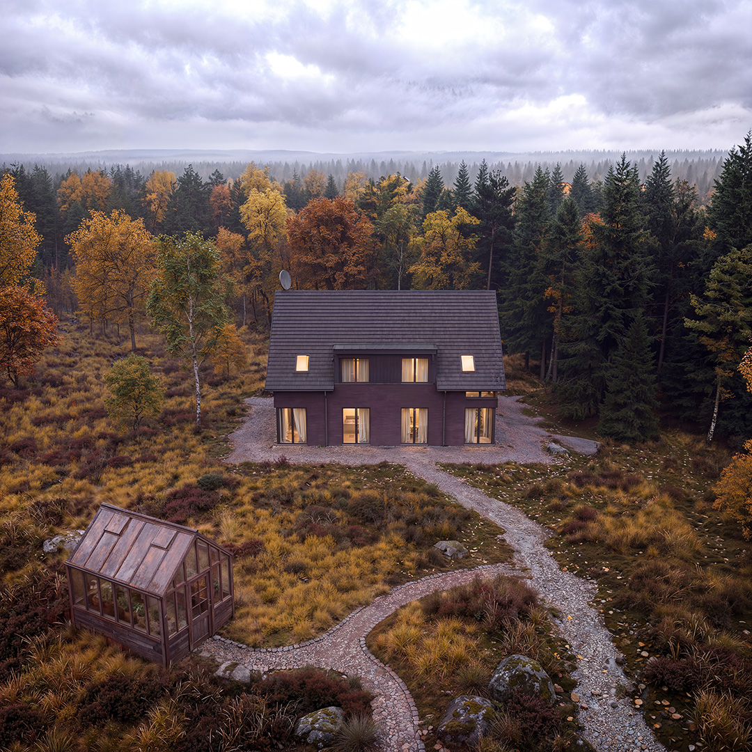 Mittels KI erstelltes Architekturbild aus der Vogelperspektive: modernes Einfamilienhaus mit anthrazitfarbenem Satteldach in herbstlichem Mischwald, geschwungener Kiesweg, freistehendes Holzgewächshaus im Vordergrund, Schwarzwälder Waldpanorama bis zum Horizont